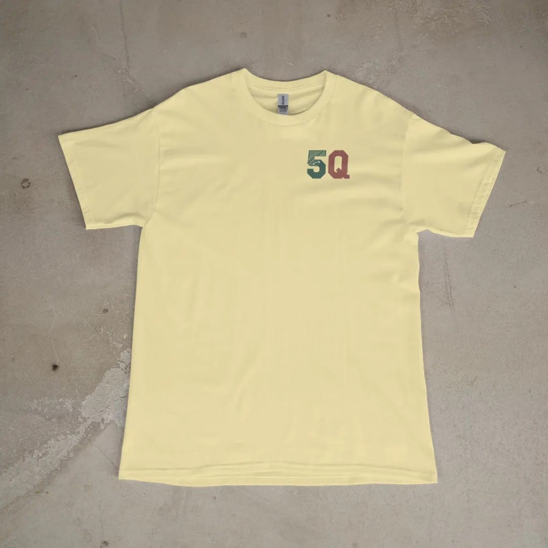 Front of a Butter tee laid flat, with the small Fifth Quarter Tailgate logo on the left chest.