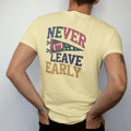 Man wearing a Butter tee, seen from the back: a felt pennant with a football and stars, with "NEVER LEAVE EARLY" in chunky rounded 70s varsity letters, printed in faded stadium green, washed brick red, faded navy and mustard with a cracked, worn…