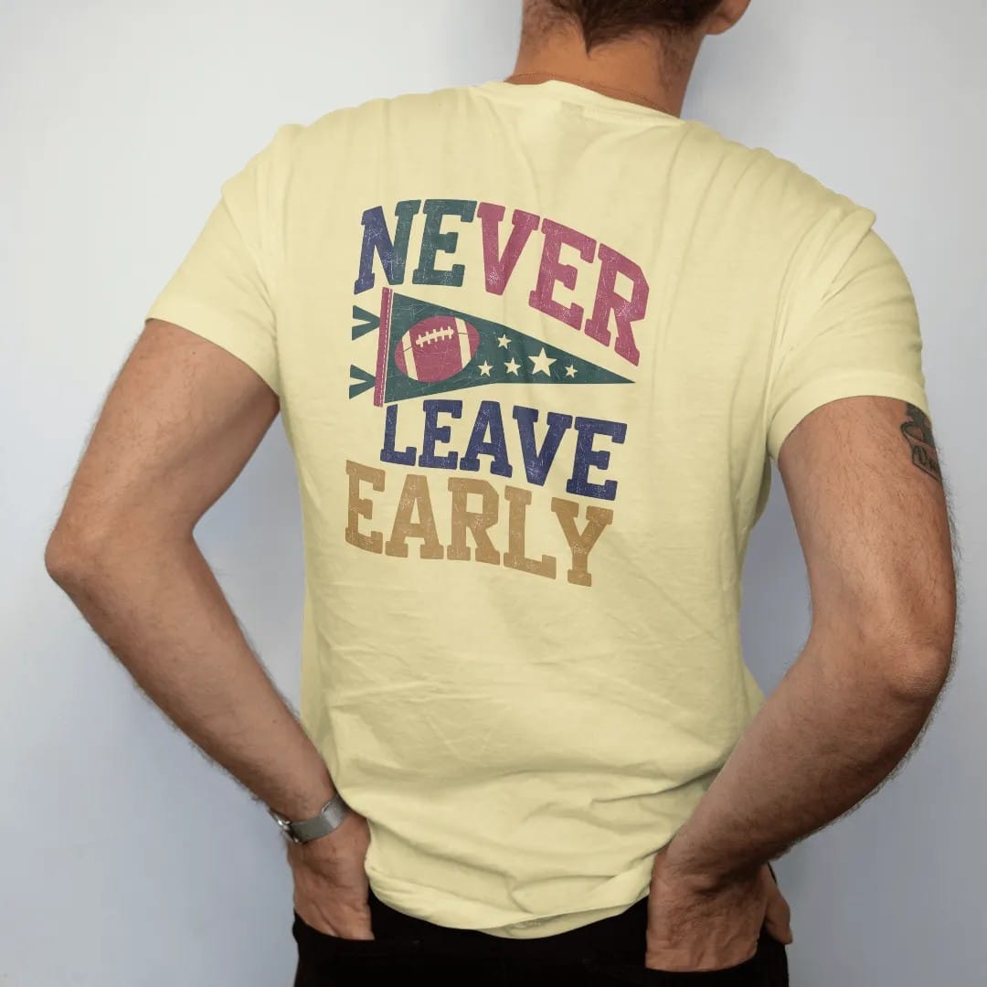Man wearing a Butter tee, seen from the back: a felt pennant with a football and stars, with "NEVER LEAVE EARLY" in chunky rounded 70s varsity letters, printed in faded stadium green, washed brick red, faded navy and mustard with a cracked, worn…
