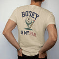 Man wearing a Sandstone tee, seen from the back: a ball resting on a tee next to a stubby scorecard pencil, with a smiley face on the ball, with "BOGEY" and "IS MY PAR" in chunky faded collegiate block letters, printed in faded fairway green,…