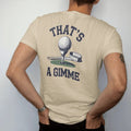 Man wearing a Sandstone tee, seen from the back: a golf ball resting a few inches from the cup with a measuring tape stretched beside it, with "THAT'S" and "A GIMME" in loopy 1970s script, printed in faded fairway green, washed navy, faded flag red…