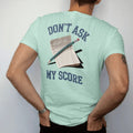 Man wearing a Chalky Mint tee, seen from the back: a stubby golf pencil on top of a crumpled scorecard, with "DON'T ASK" and "MY SCORE" in chunky faded collegiate block letters, printed in faded fairway green, washed navy, faded flag red and sand…