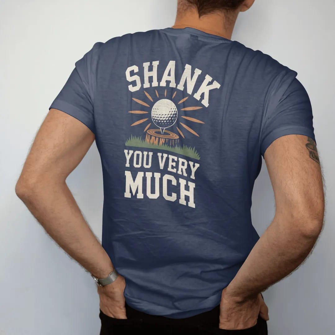 Man wearing a Navy tee, seen from the back: a golf ball ricocheting off a tree trunk with starbursts, with "SHANK" and "YOU VERY MUCH" in chunky faded collegiate block letters, printed in faded clubhouse cream, sage grass green, washed flag red and…