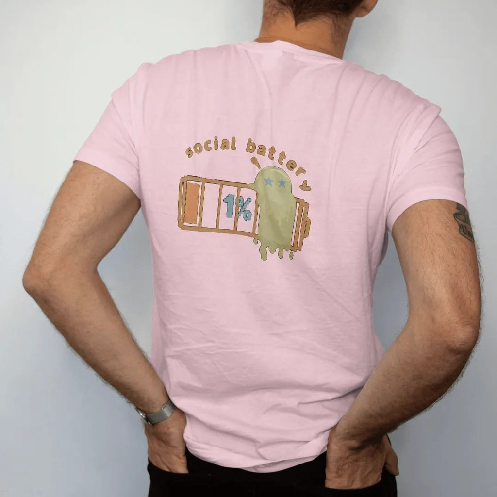Man wearing a Blossom tee, seen from the back: blip the pixel slime melting against a nearly empty pixel battery reading 1%, under social battery in brown and rust rounded letters.