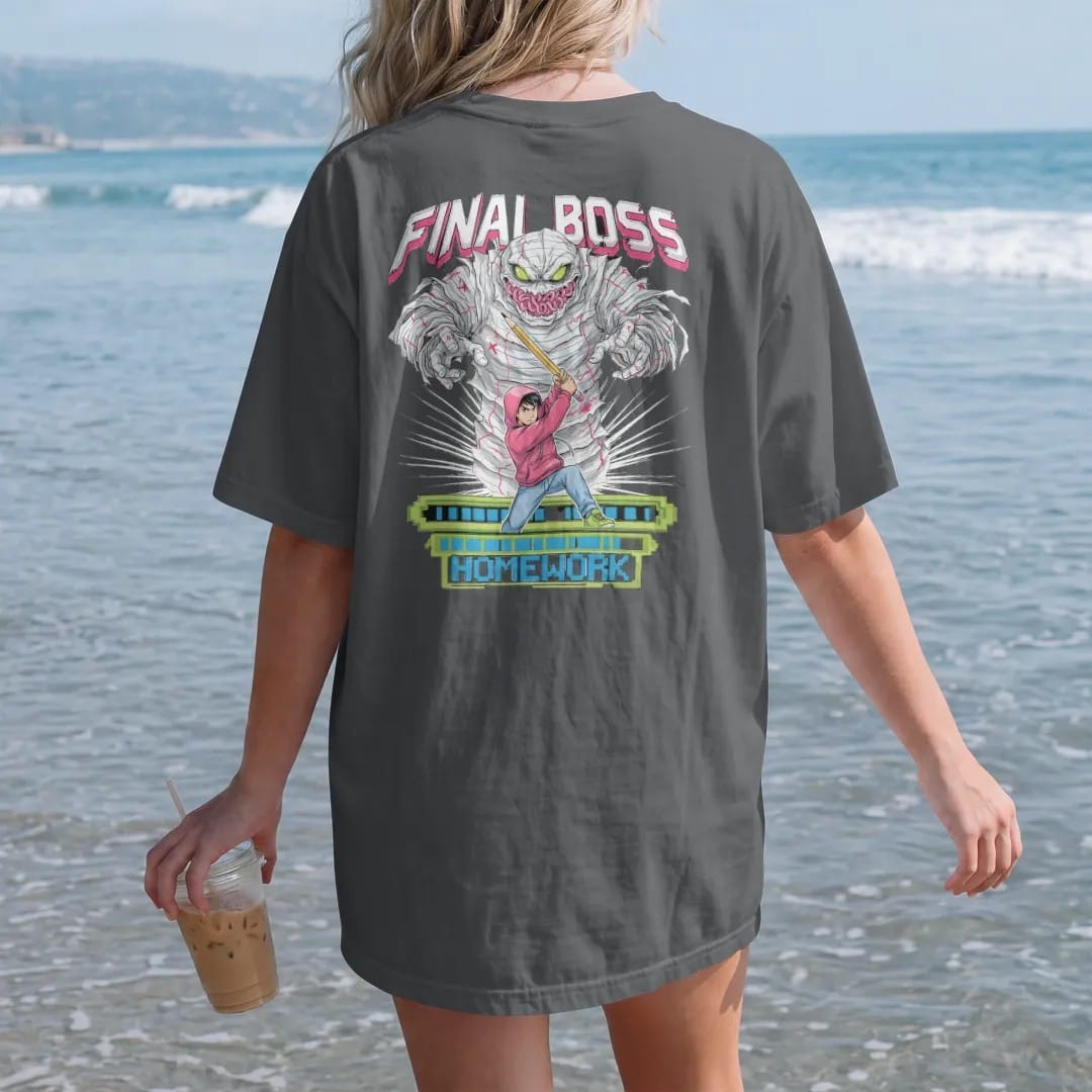 Woman on the beach in a Graphite tee, back view: an anime-style teen with a giant pencil sword facing a worksheet monster, with final boss in jagged arcade letters and homework on a pixel health bar, in pink, lime, blue and silver.