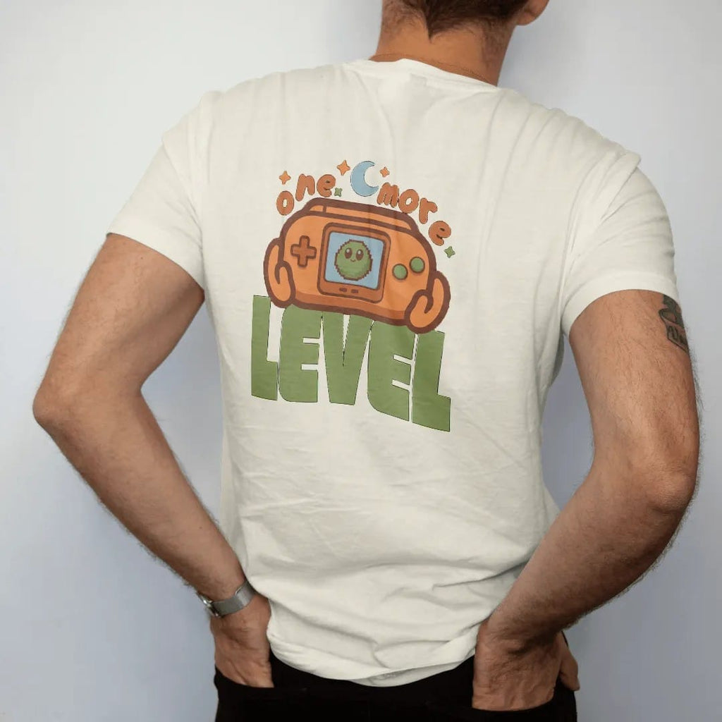 Man wearing a Ivory tee, seen from the back: a generic retro handheld console showing Blip the pixel slime, held under a moon and stars, with one more in arcade letters and level in big block type, in brown, rust, moss and denim.