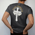 Man wearing a Black tee, seen from the back: an ornate rhinestone-textured gothic cross with small wings and a static halo, under Divine Frequency in arched blackletter, in bone cream, chrome silver and antique gold.