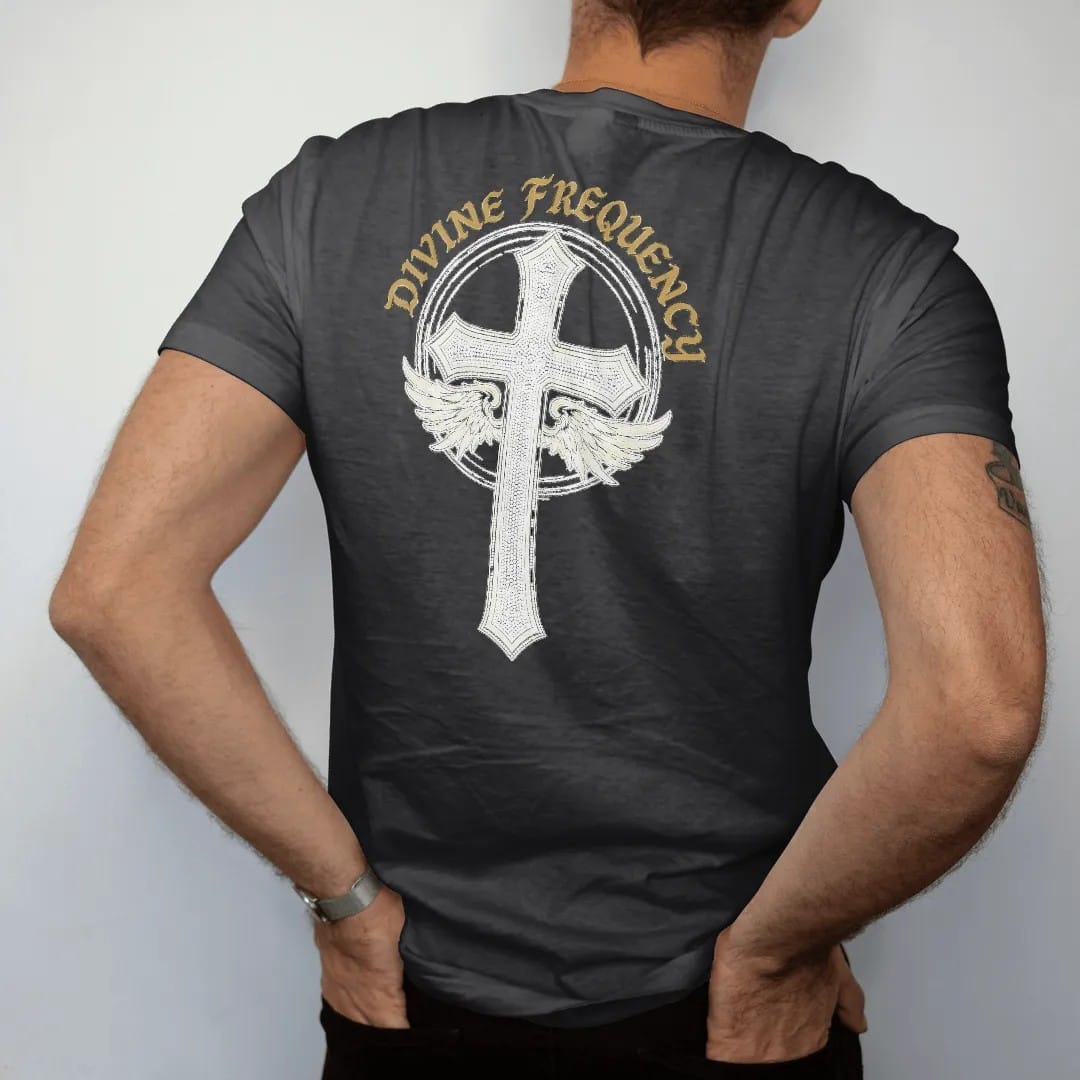 Man wearing a Black tee, seen from the back: an ornate rhinestone-textured gothic cross with small wings and a static halo, under Divine Frequency in arched blackletter, in bone cream, chrome silver and antique gold.