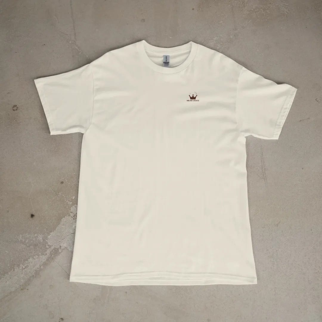 Front of a Ivory tee laid flat, with the small Velvet Static logo on the left chest.