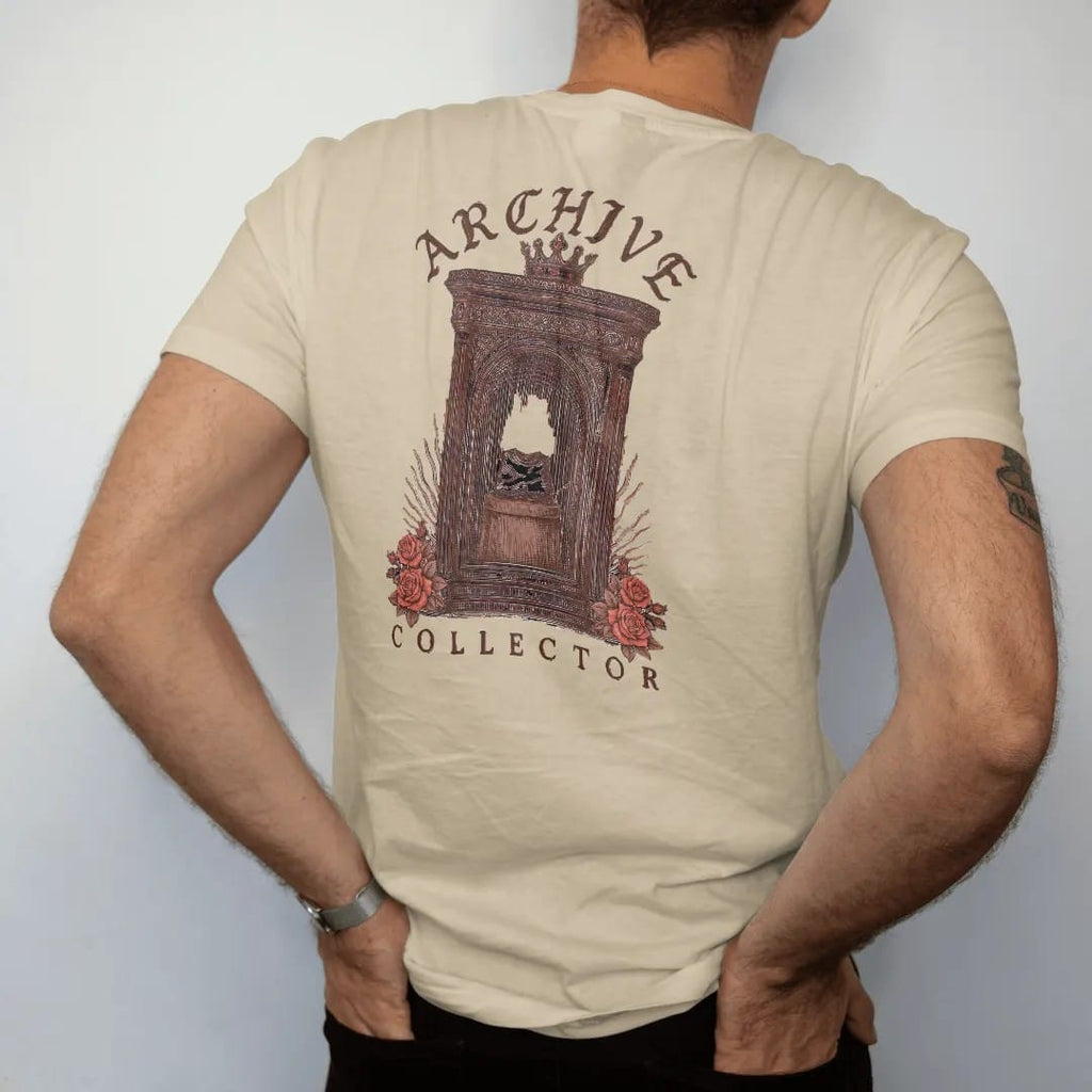 Man wearing a Sandstone tee, seen from the back: a vintage display cabinet holding a single folded tee on a pedestal with a crown above and roses below, under Archive in blackletter and above Collector in serif capitals, in espresso, oxblood and…