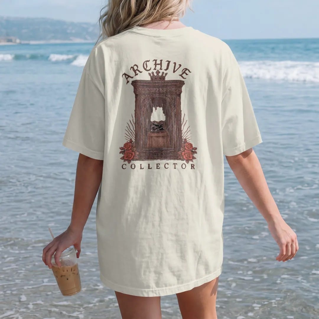 Woman on the beach in a Ivory tee, back view: a vintage display cabinet holding a single folded tee on a pedestal with a crown above and roses below, under Archive in blackletter and above Collector in serif capitals, in espresso, oxblood and bronze.