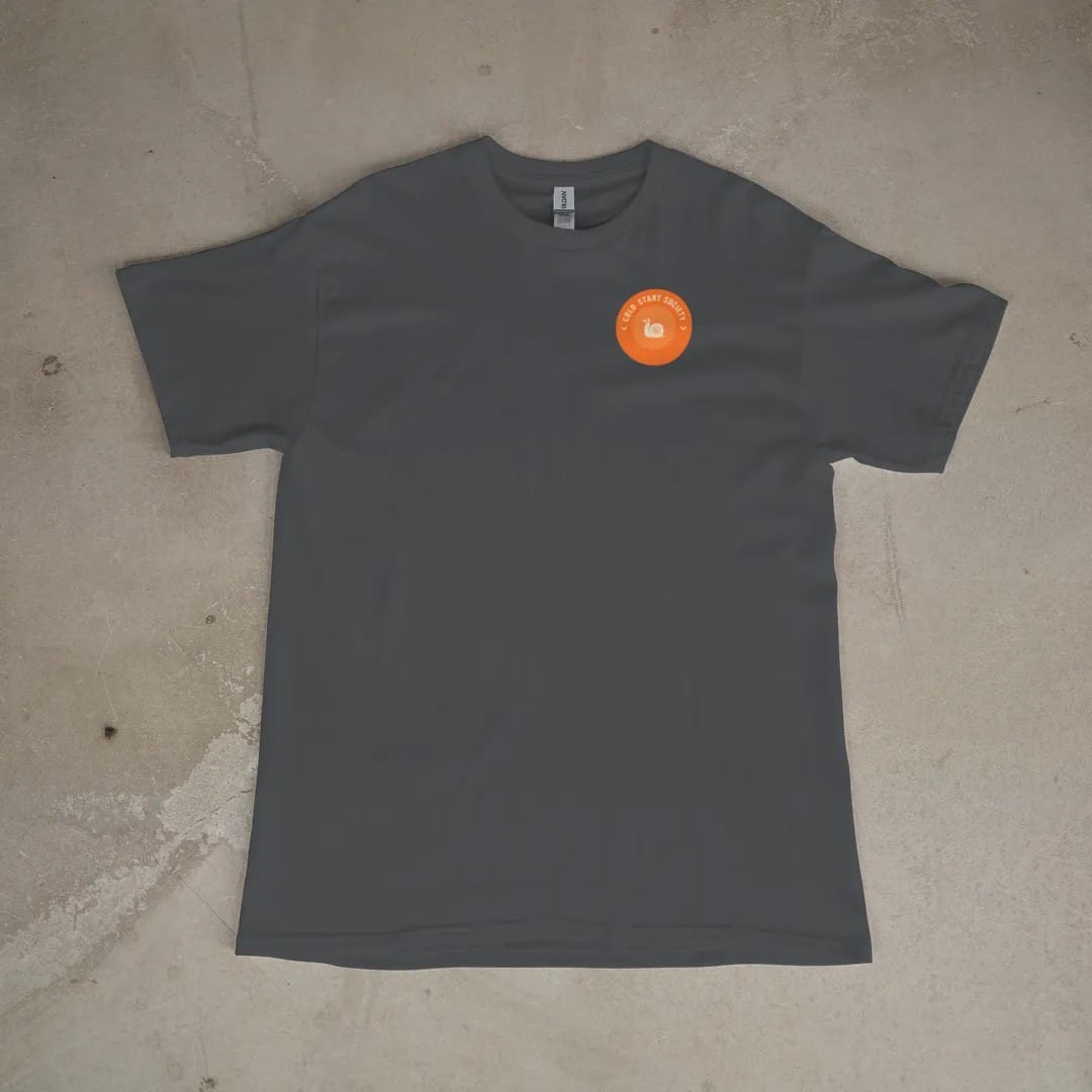 Front of a Graphite tee laid flat, with the small Cold Start Society logo on the left chest.