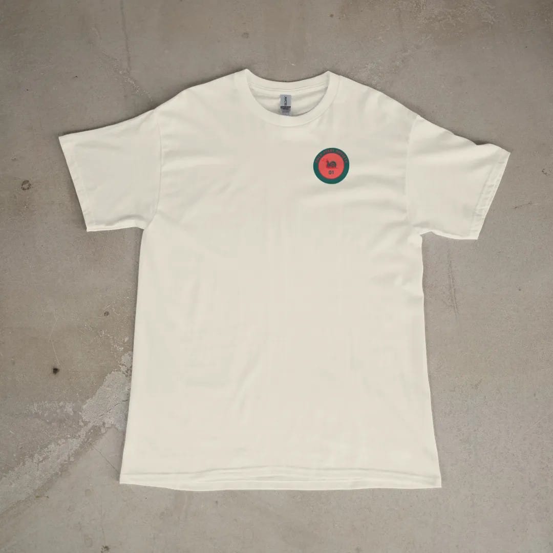 Front of a Ivory tee laid flat, with the small Cold Start Society logo on the left chest.
