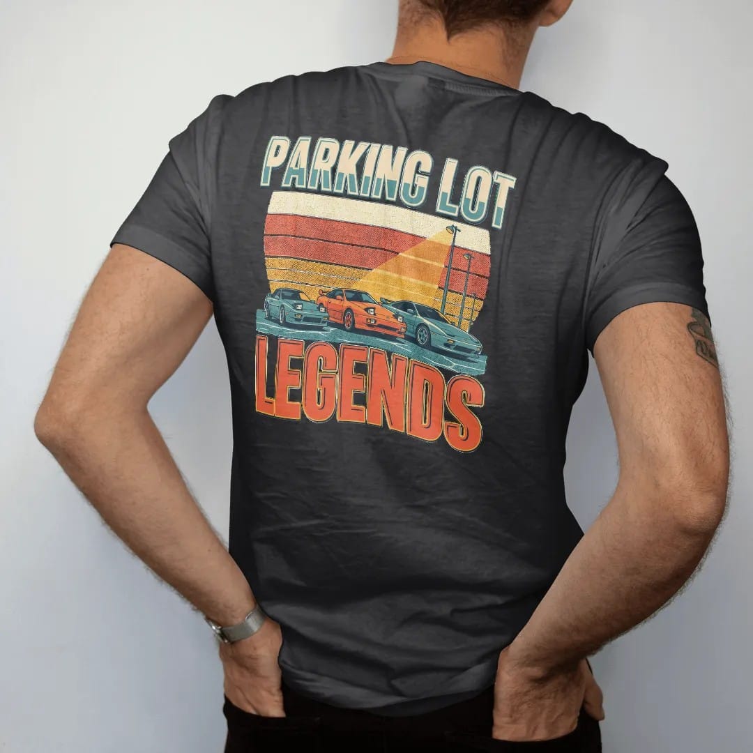 Man wearing a Black tee, seen from the back: three generic sport coupes under a parking-lot light with a striped retro sunset, Parking Lot Legends in big poster type, in cream, orange, yellow and teal.