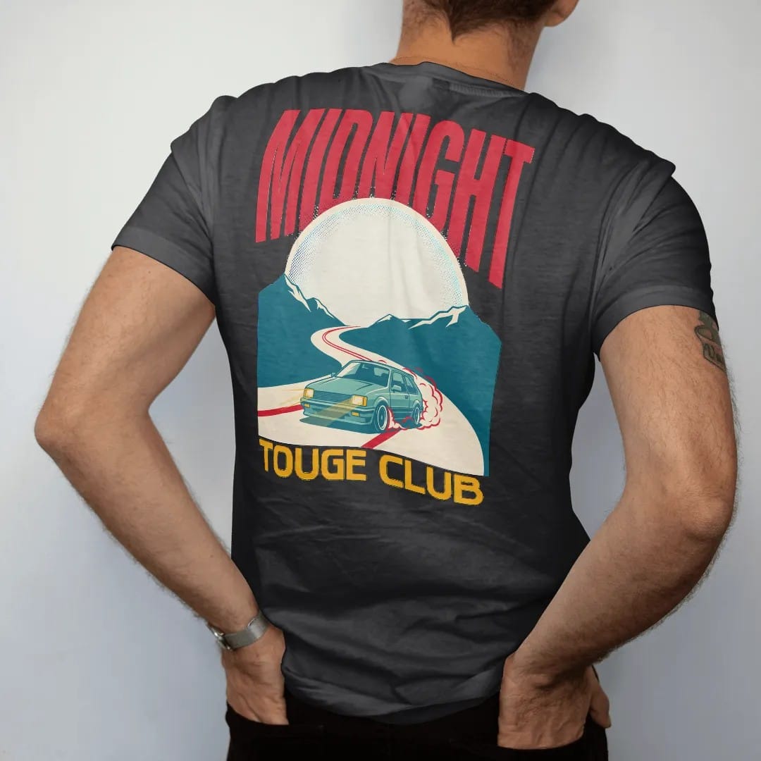 Man wearing a Black tee, seen from the back: a generic 90s hatchback drifting a moonlit mountain hairpin in a Japanese poster layout with Midnight Touge Club lettering, in cream, red, yellow and teal.
