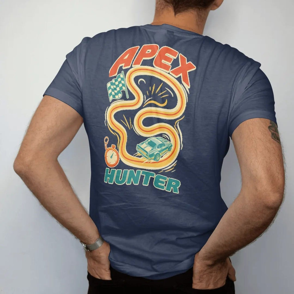 Man wearing a Navy tee, seen from the back: a winding race-track map with a glowing racing line, checkered flag and a generic race car diving into a turn, with Apex Hunter lettering, in cream, orange, teal and yellow.