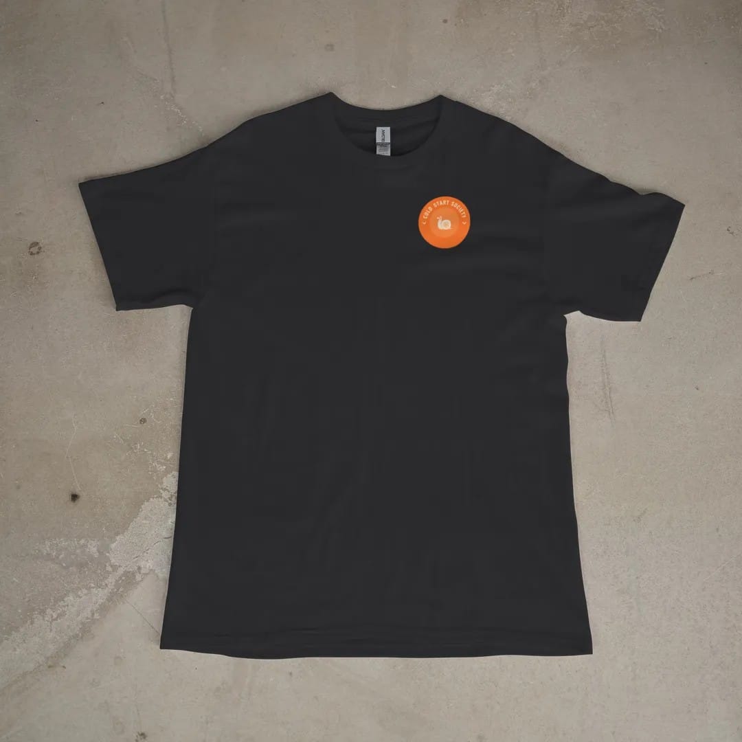 Front of a Black tee laid flat, with the small Cold Start Society logo on the left chest.