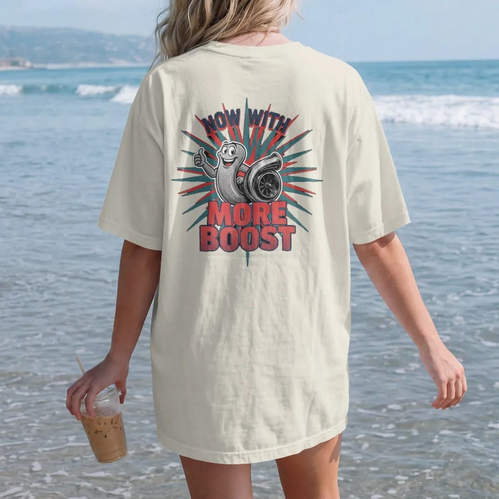 Woman on the beach in a Ivory tee, back view: a vintage-ad turbo snail mascot giving a thumbs up beside a turbocharger on a starburst, Now With More Boost lettering, in navy, rally red, teal and charcoal.