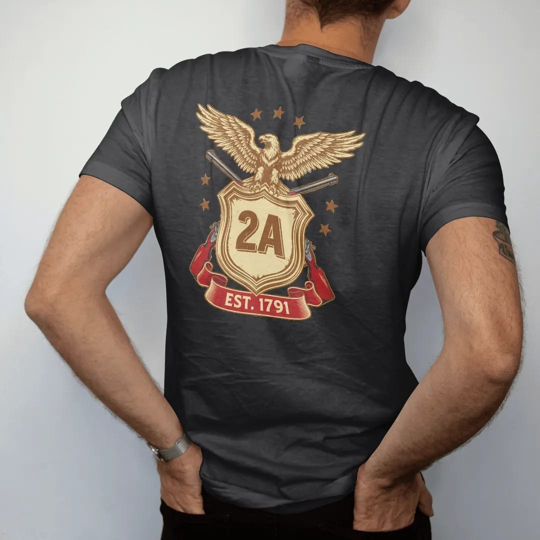Man wearing a Black tee, seen from the back: a heraldic shield with 2A at the center over two crossed generic rifles and a spread-winged eagle, Est. 1791 on a ribbon, in brass gold, cream, red and blue.