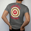 Man wearing a Pepper tee, seen from the back: a bullseye target with a tight center cluster and bold tick marks, Aim Small Miss Small in stencil letters, in cream, red and brass gold.