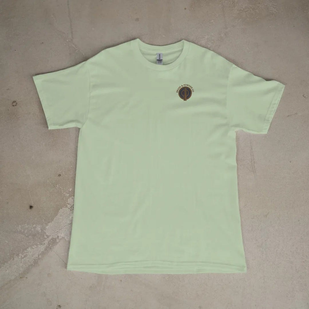 Front of a Light Green tee laid flat, with the small Brass & Powder Co. logo on the left chest.