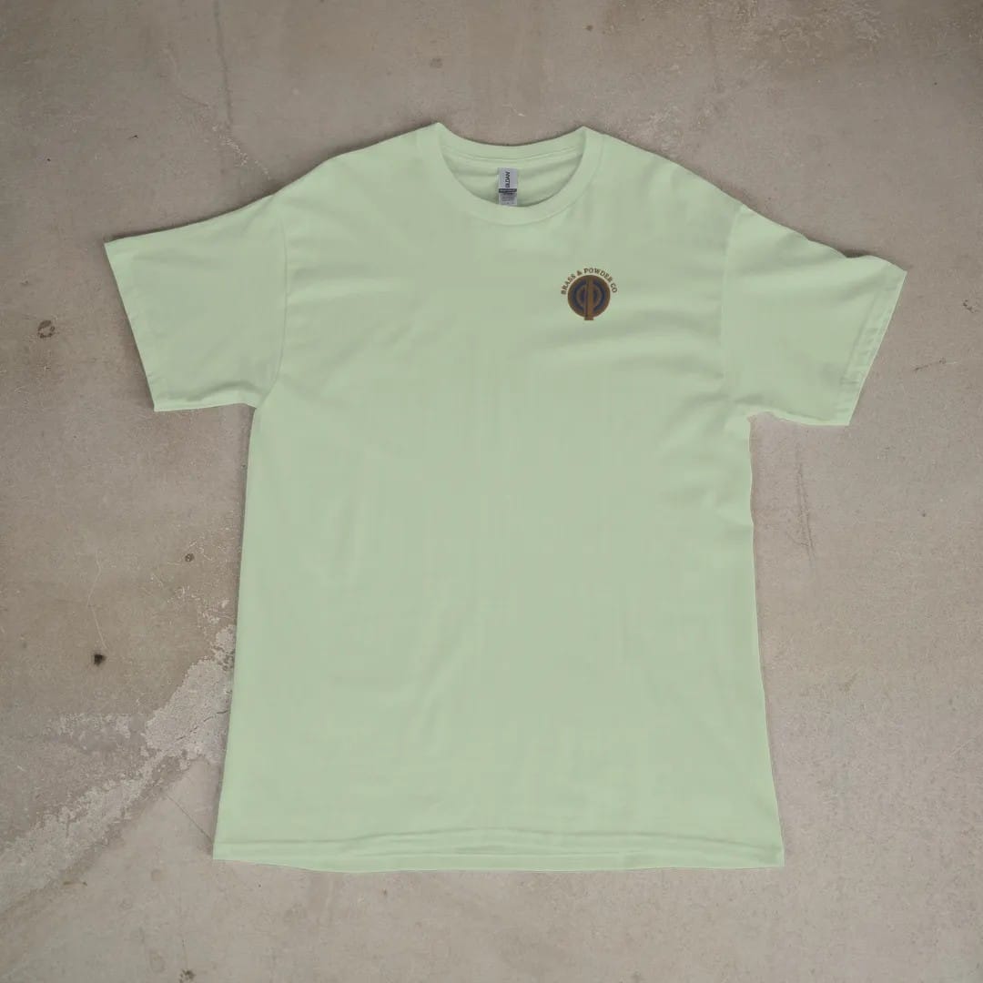 Front of a Light Green tee laid flat, with the small Brass & Powder Co. logo on the left chest.