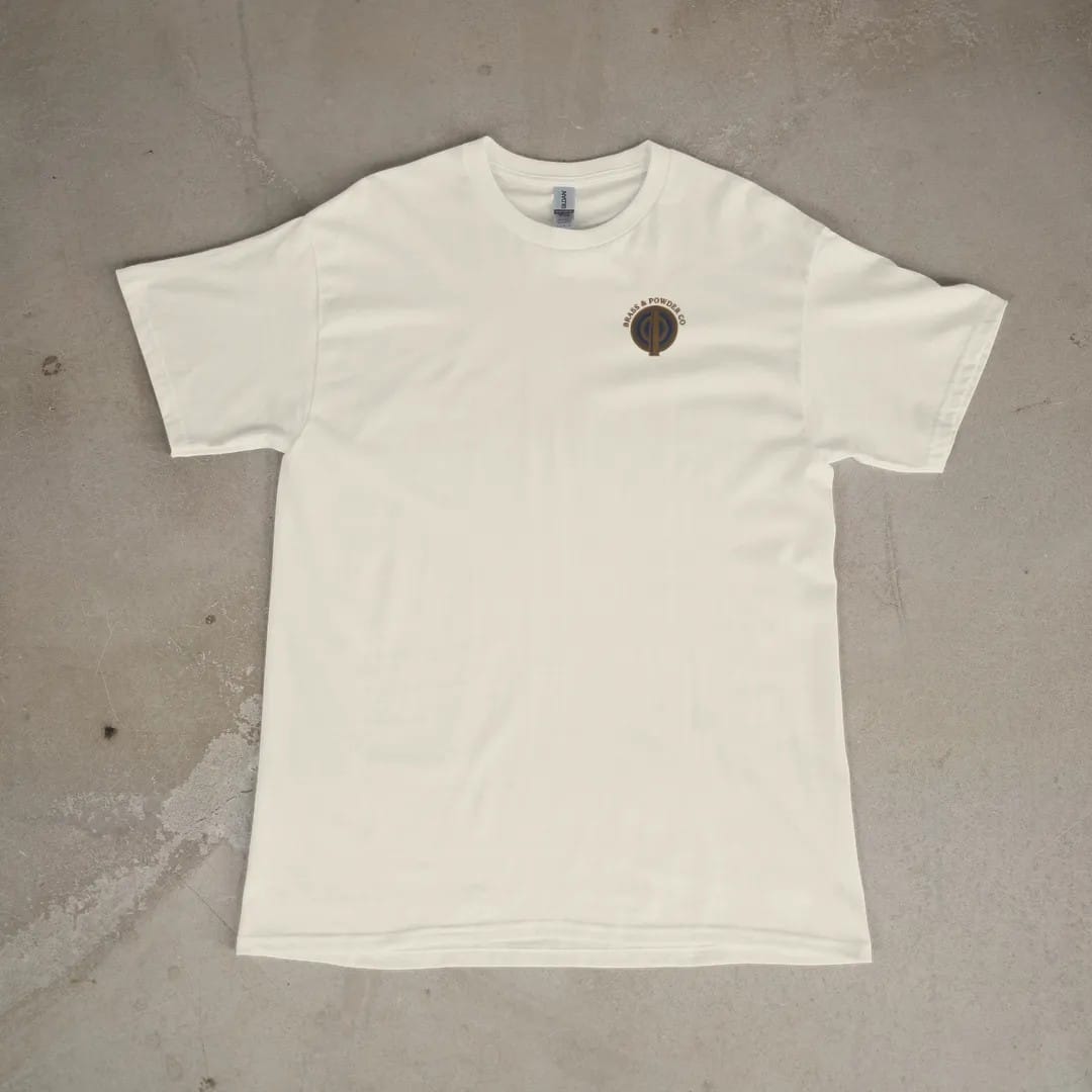 Front of a Ivory tee laid flat, with the small Brass & Powder Co. logo on the left chest.