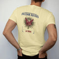 Man wearing a Butter tee, seen from the back: a vintage ammo-box label with ornate corners, a red eagle and one brass cartridge on starburst rays, Freedom Rounds above and 50 Count below.