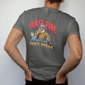 Man wearing a Pepper tee, seen from the back: the bald eagle mascot in hearing protection eating a sandwich behind a range bench and cooler with a generic pistol locked open, Cease Fire Snack Break lettering, in brass gold, cream, red and blue.