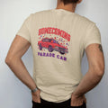 Man wearing a Sandstone tee, seen from the back: a boxy 80s sedan dressed with streamers and pom-poms among falling leaves, under Homecoming and over Parade Car, in deep red, purple and gunmetal.