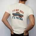 Man wearing a Ivory tee, seen from the back: a weathered teal square-body pickup with rust patches, It's Not Rust above and It's Patina below in bold block letters.
