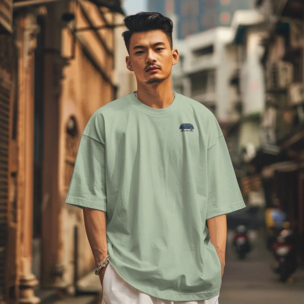 Man in a Light Green tee on a city street, with the small Square Body Social logo on the left chest.