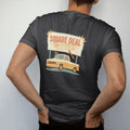 Man wearing a Black tee, seen from the back: a retro roadside dealership sign with starbursts over a square-body pickup with a sale flag, reading Square Deal over Motors.
