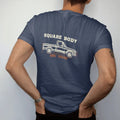 Man wearing a Navy tee, seen from the back: a cream line blueprint of a square-body pickup in side profile with dimension arrows, Square Body above and Spec Sheet below.