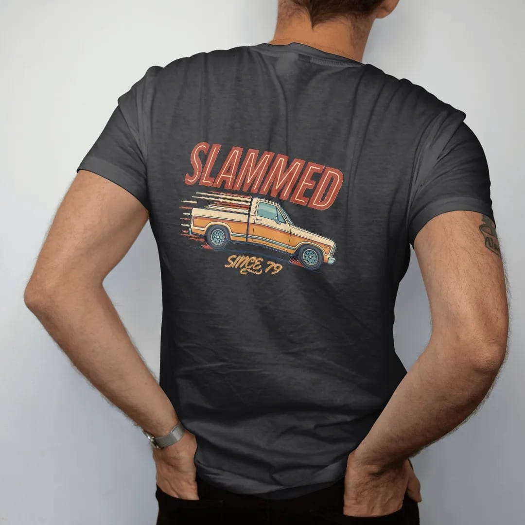 Man wearing a Black tee, seen from the back: a lowered square-body pickup inches off the road with sparks and speed lines, under Slammed and over Since '79.