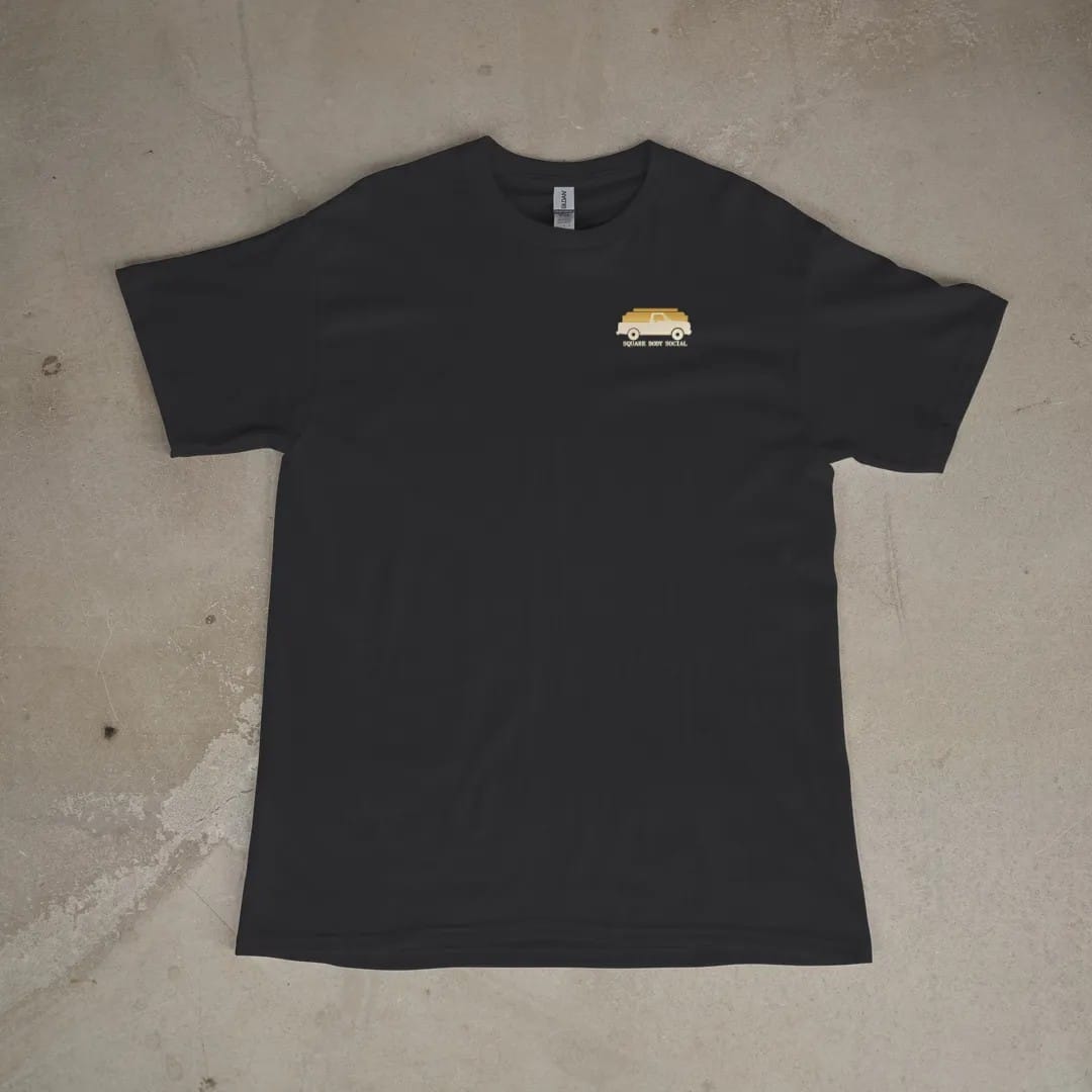 Front of a Black tee laid flat, with the small Square Body Social logo on the left chest.