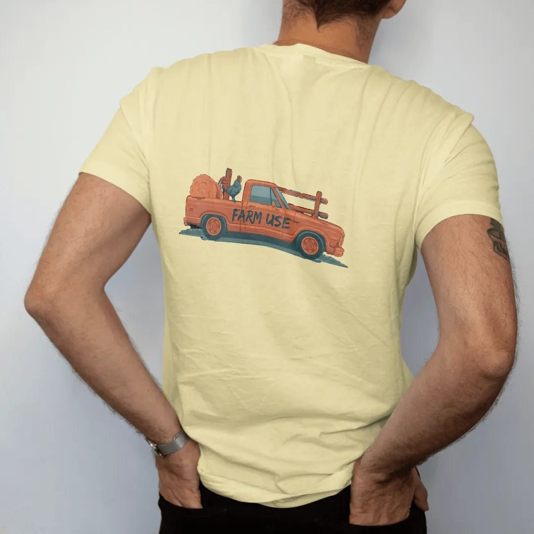 Man wearing a Butter tee, seen from the back: a dented farm square-body pickup with Farm Use hand-painted on the door, a hay bale and a rooster in the bed, in rust, teal and navy.