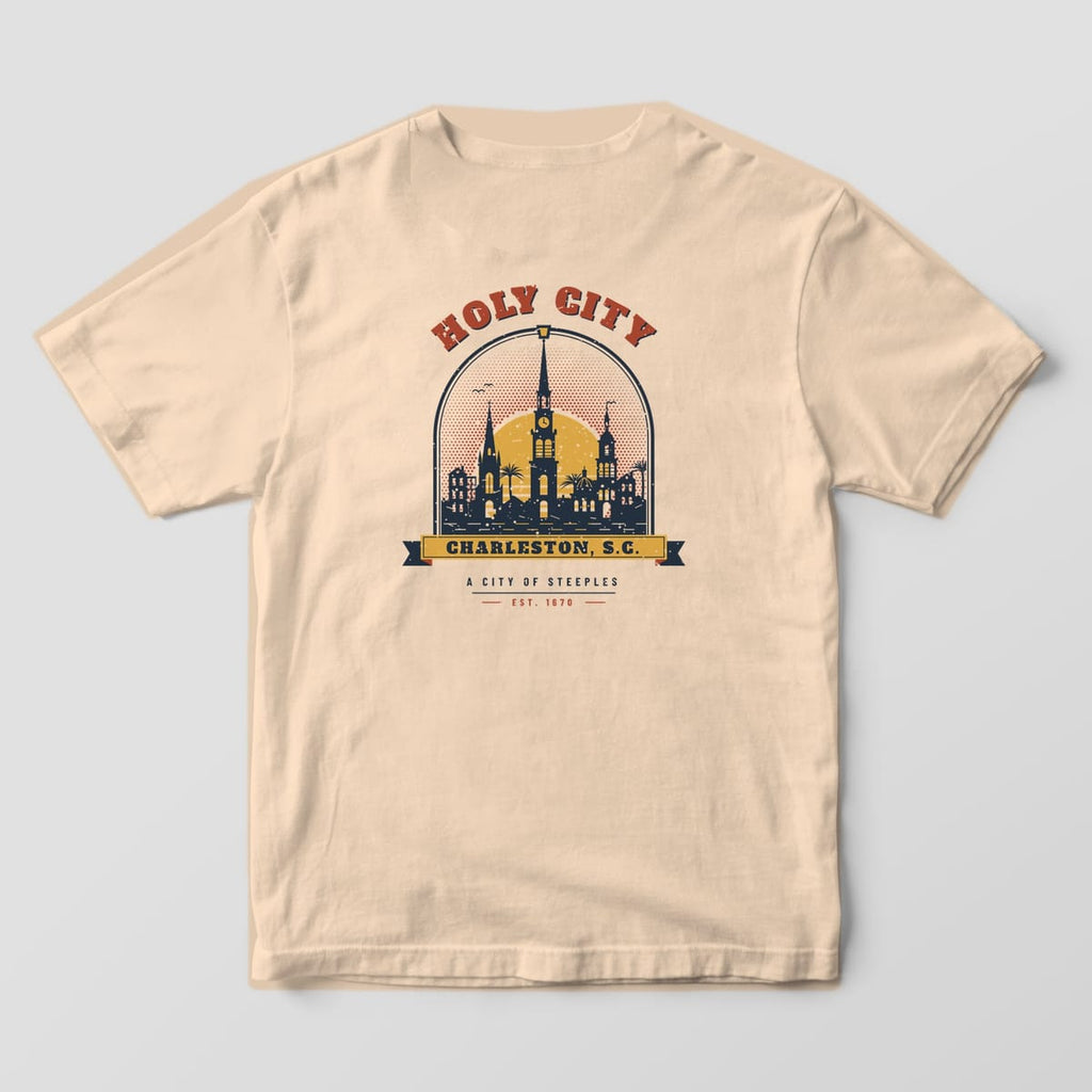 Back of an Ivory Comfort Colors 1717 tee with a navy, brick red and gold Holy City badge: church steeples and palmettos inside an arched window over a Charleston, S.C. banner.