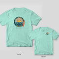 Chalky Mint Comfort Colors tee shown back and front: a retro Folly Beach Surf Club badge with sunburst, waves and longboard on the back and a small wave circle on the chest.