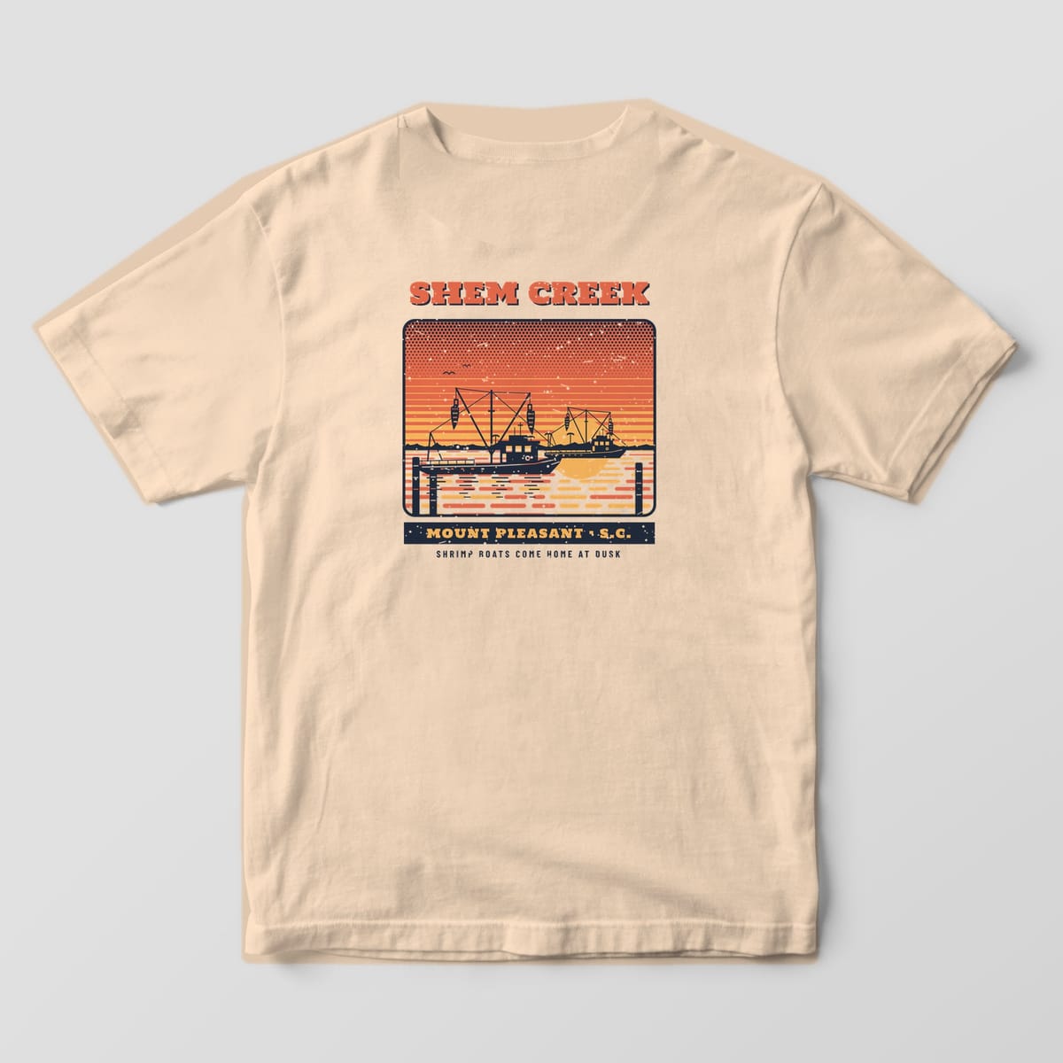 Back of an Ivory Comfort Colors 1717 tee with two navy shrimp trawlers with raised outriggers and nets against a coral and gold striped sunset, titled Shem Creek, Mount Pleasant S.C.