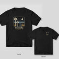 Black Comfort Colors tee shown back and front: a night marsh scene with palmettos and a crescent moon on the back and a small palmetto and moon on the left chest.