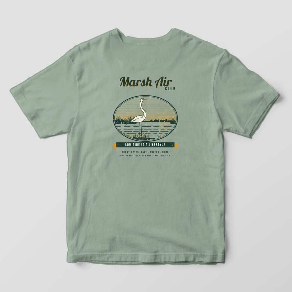 Back of a Bay Comfort Colors 1717 tee with a dark green, cream and gold club badge: a great egret in a marsh oval, aroma lines over the water, and Low Tide Is a Lifestyle.