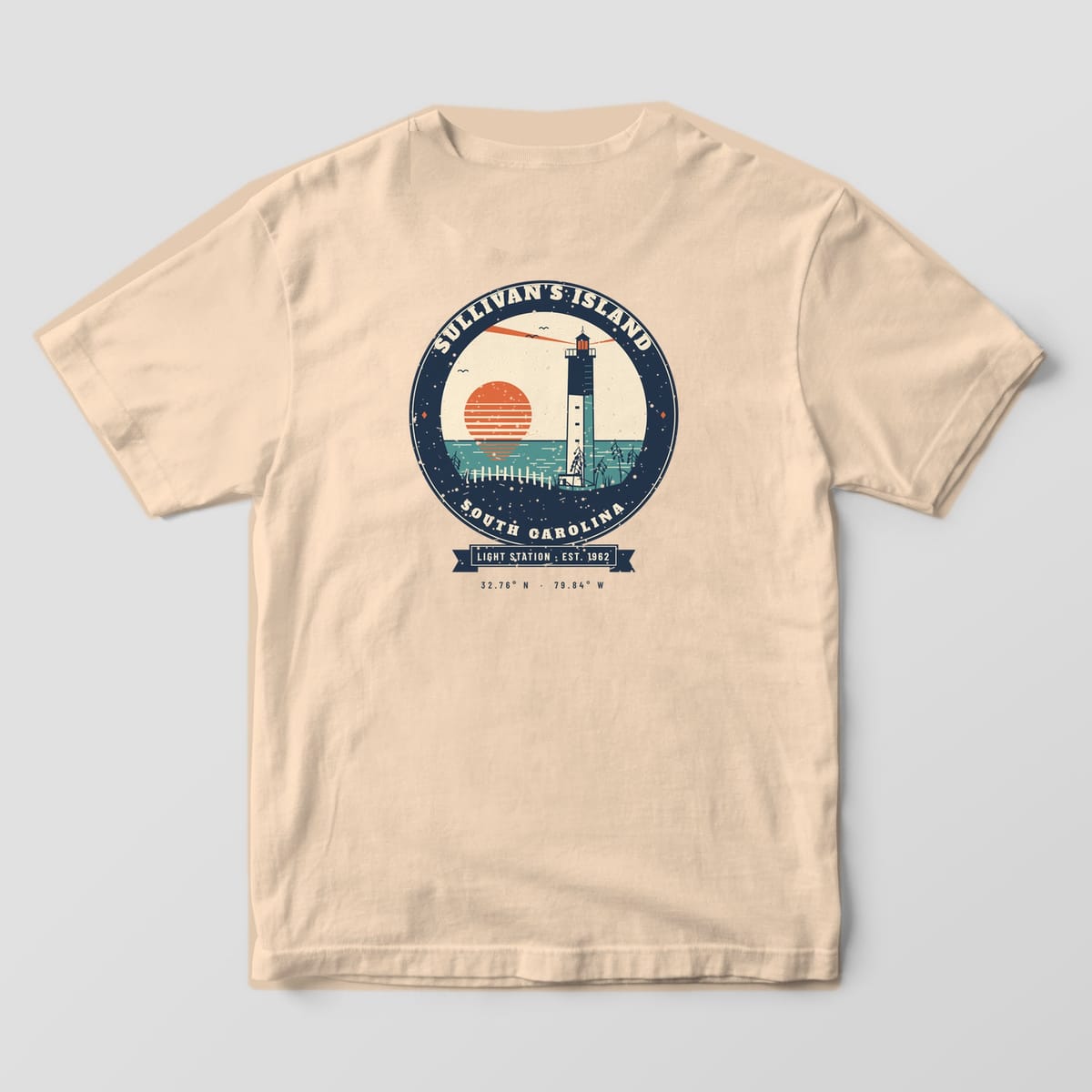 Back of a Ivory Comfort Colors 1717 tee with a navy, coral and teal badge of the triangular Sullivan's Island lighthouse at sunrise over sea oats.