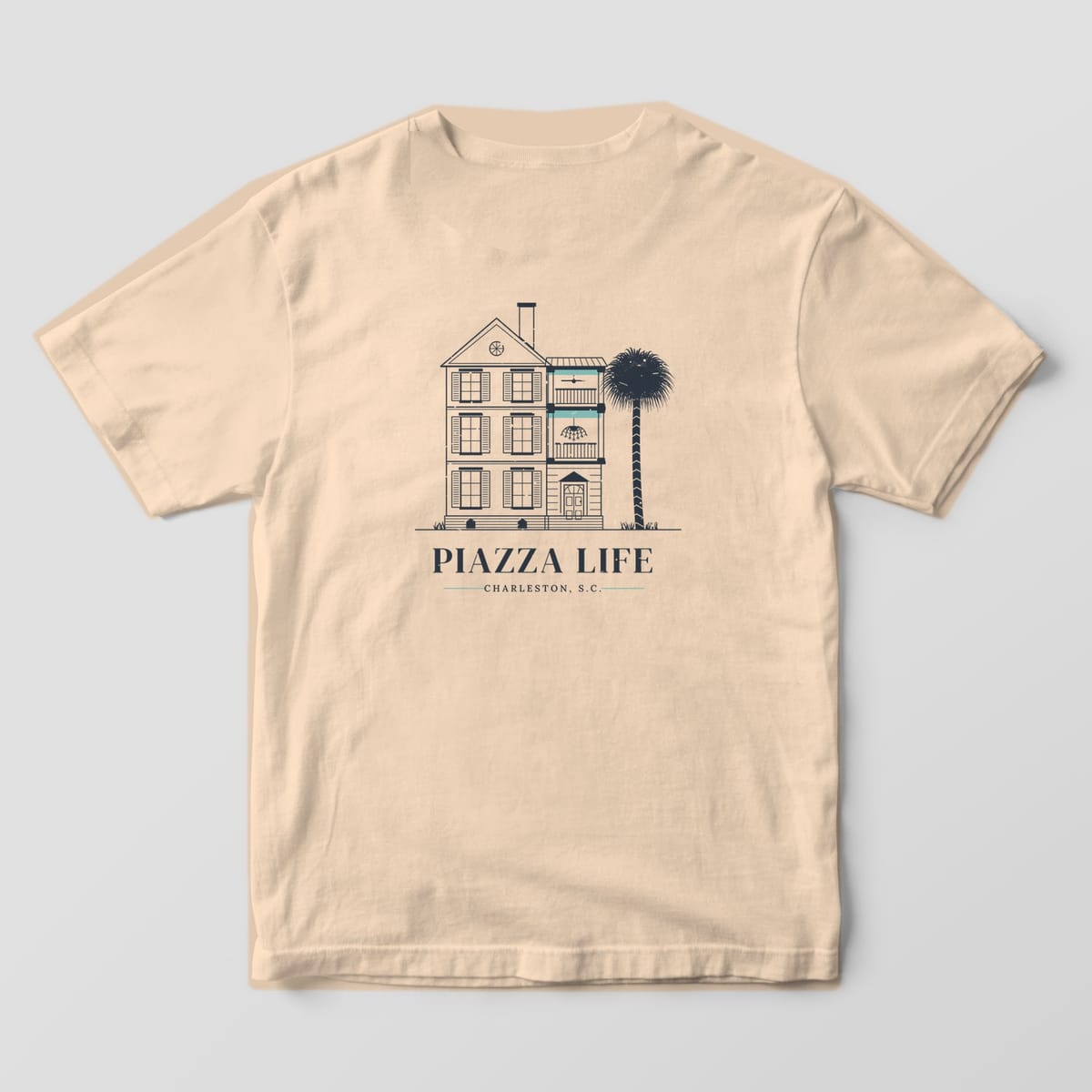 Back of a Ivory Comfort Colors 1717 tee with a charcoal line drawing of a Charleston single house with haint blue piazza ceilings above the words Piazza Life.
