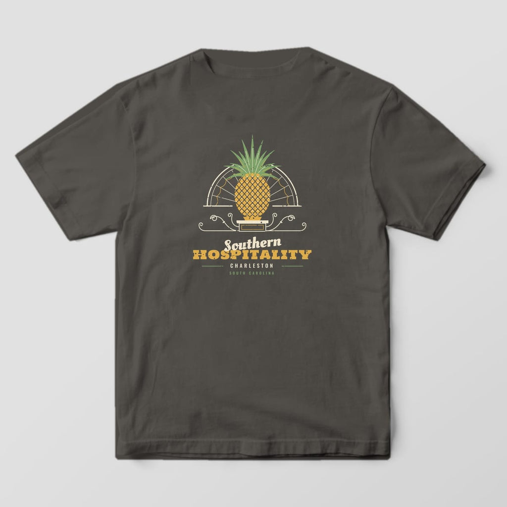 Back of a Pepper Comfort Colors 1717 tee with a gold and green pineapple in front of a cream fanlight arch above the words Southern Hospitality, Charleston.