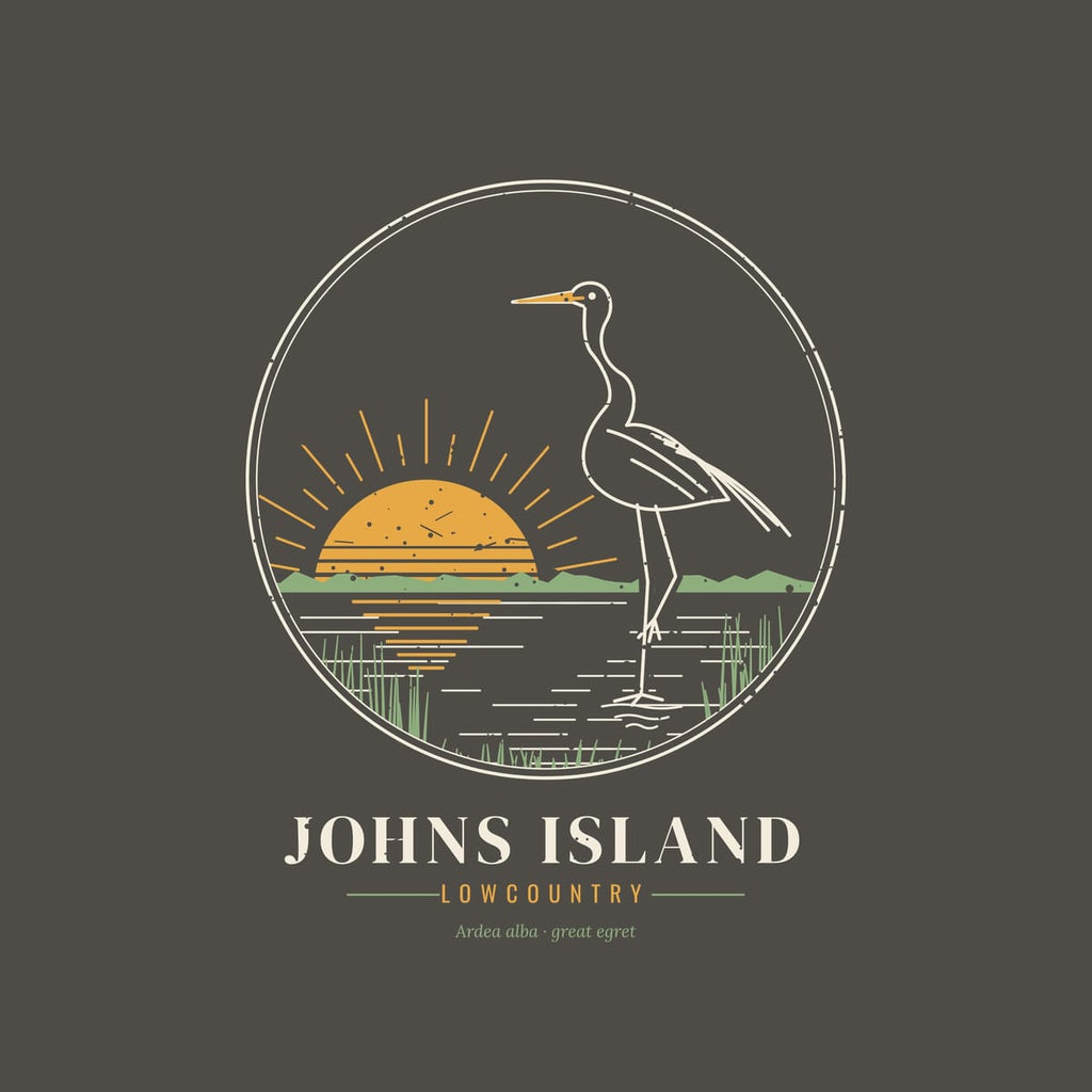Close-up of the back print: egret with a gold bill and trailing plumes, a striped rising sun, marsh treeline and spartina grass.