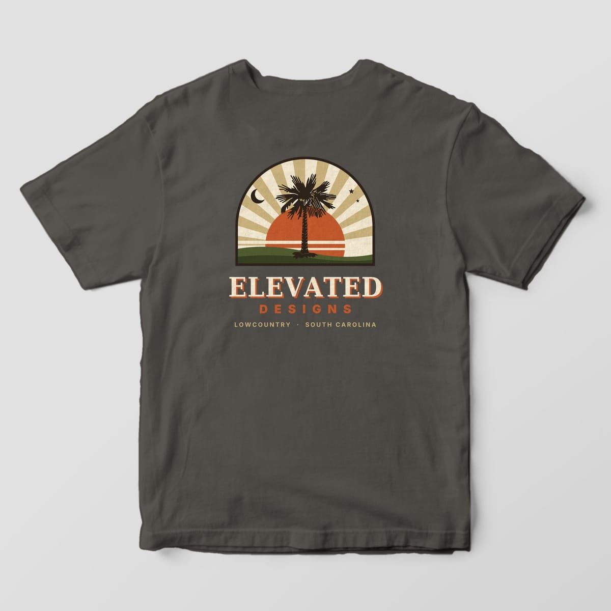 Back of a Pepper Comfort Colors 1717 tee with an arched-window scene of a palmetto in front of an orange sun and tan sunburst rays, a crescent moon and stars, with ELEVATED DESIGNS and LOWCOUNTRY · SOUTH CAROLINA below.