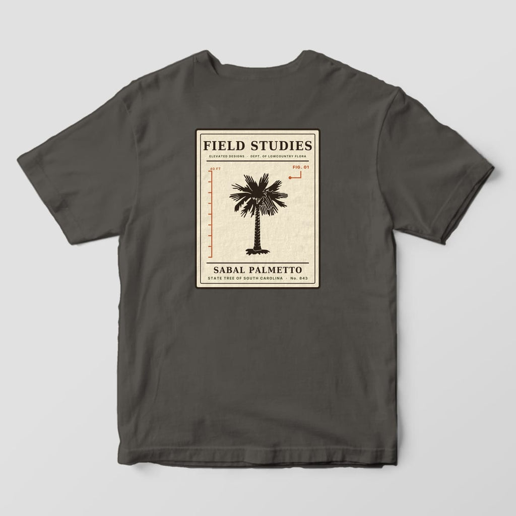 Back of a Pepper Comfort Colors 1717 tee with a cream specimen card reading FIELD STUDIES and SABAL PALMETTO, with a dark palmetto tree next to a rust 40 FT height ruler and a FIG. 01 callout.