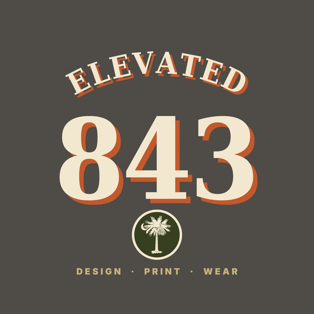 Close-up of the 843 Varsity print: cream serif numbers with a rust drop shadow and a round olive patch holding a palmetto and crescent moon.