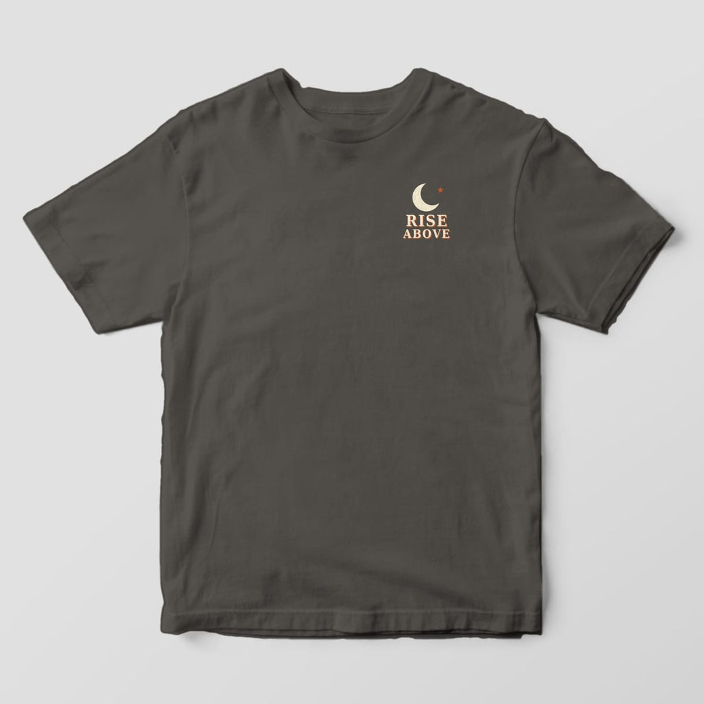 Front of a Pepper Comfort Colors 1717 tee with a small left-chest cream crescent moon and rust star above the words RISE ABOVE.